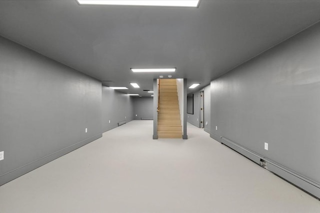 finished below grade area with baseboards, baseboard heating, and stairway