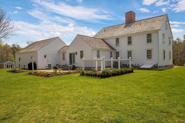 rear view of property featuring a yard and a chimney