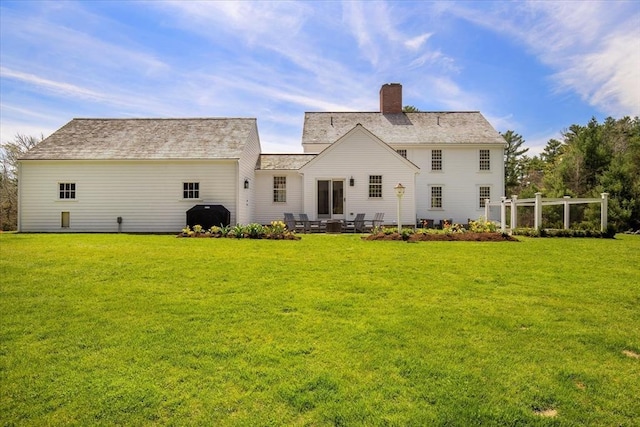 back of property with a chimney, a yard, and a patio area