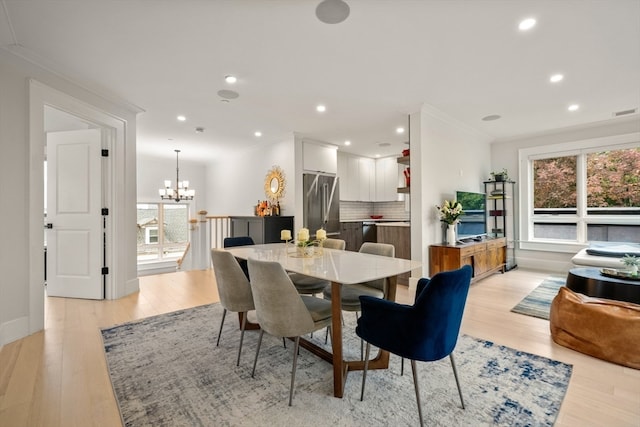 dining area with a notable chandelier, crown molding, and light hardwood / wood-style floors