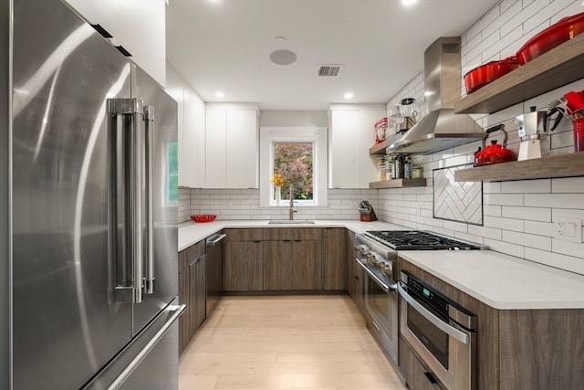 kitchen featuring white cabinetry, backsplash, exhaust hood, light hardwood / wood-style flooring, and high quality appliances