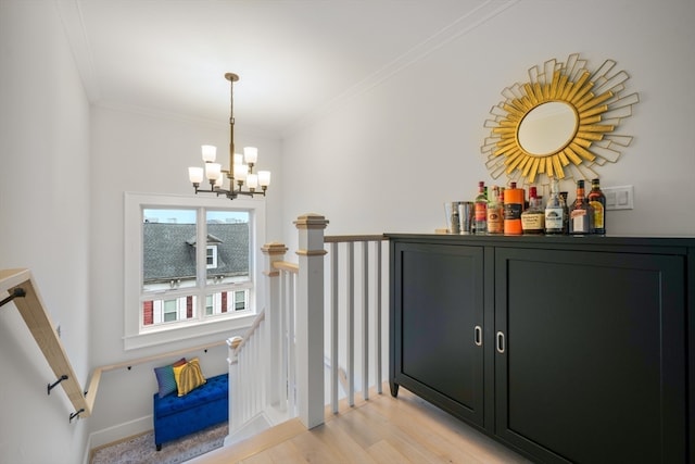 bar with ornamental molding, an inviting chandelier, and light hardwood / wood-style flooring