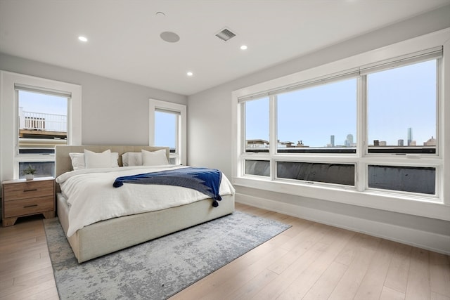 bedroom with light hardwood / wood-style floors and multiple windows