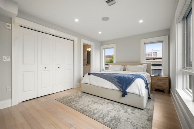 bedroom with ensuite bathroom, light hardwood / wood-style flooring, and a closet