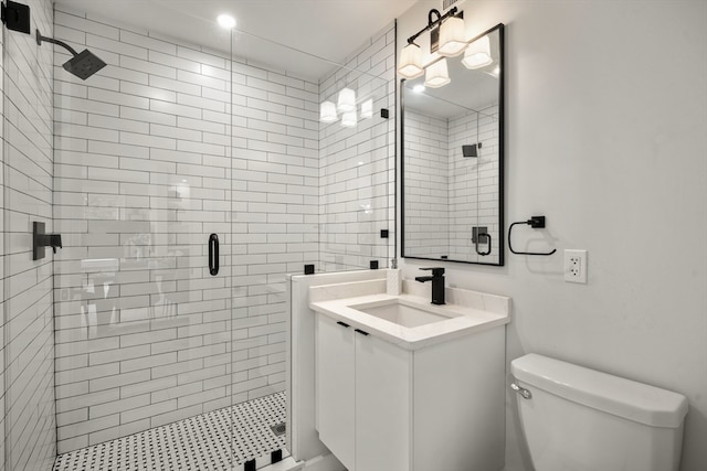 bathroom with a shower with shower door, vanity, and toilet