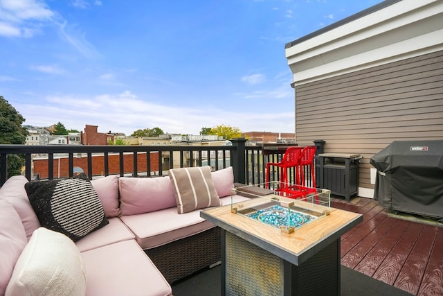 wooden terrace with grilling area and an outdoor living space with a fire pit