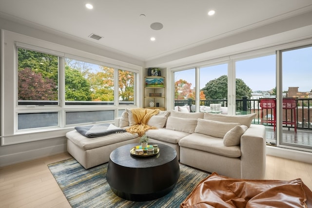 living room featuring wood-type flooring, ornamental molding, and plenty of natural light