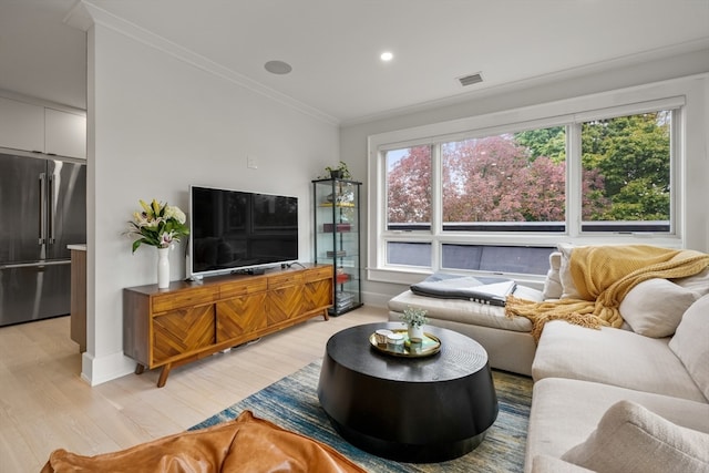 living room featuring light wood-type flooring, crown molding, and a healthy amount of sunlight