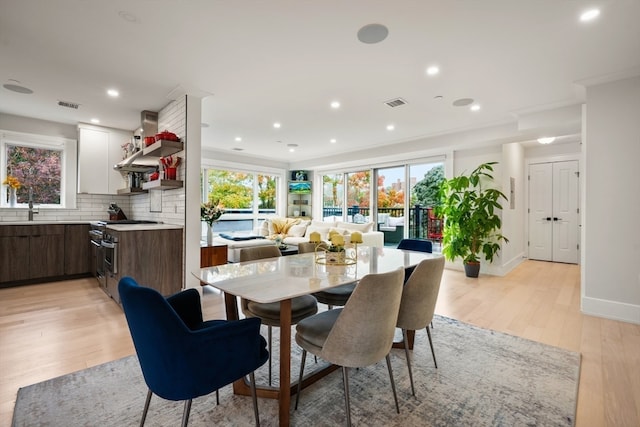 dining space with ornamental molding and light wood-type flooring