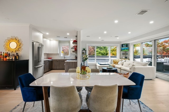 dining area featuring ornamental molding and light hardwood / wood-style flooring