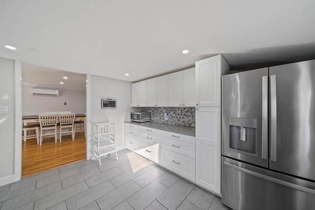 kitchen featuring stainless steel appliances, white cabinetry, tasteful backsplash, and a wall mounted AC