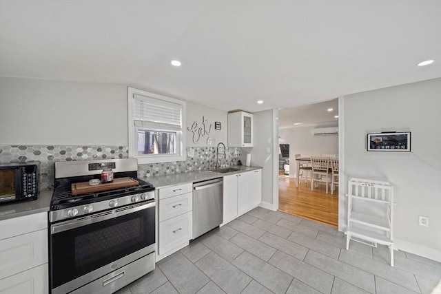 kitchen featuring sink, white cabinetry, stainless steel appliances, tasteful backsplash, and an AC wall unit