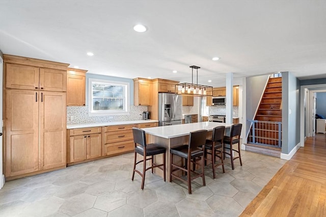 12 Babson St, Wakefield, MA 01880 - kitchen featuring stainless steel appliances, decorative backsplash, light countertops, recessed lighting, and a kitchen breakfast bar