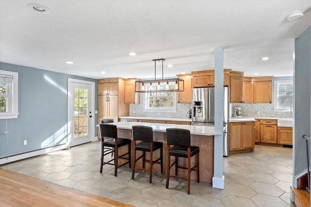 12 Babson St, Wakefield, MA 01880 - kitchen with stainless steel fridge with ice dispenser, a kitchen island, light countertops, backsplash, and healthy amount of natural light