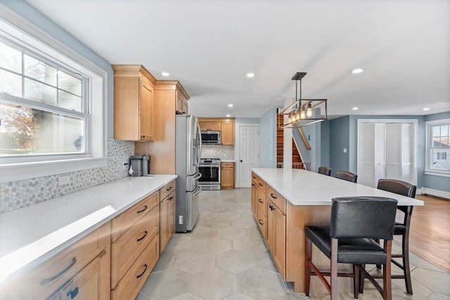 12 Babson St, Wakefield, MA 01880 - kitchen with stainless steel appliances, a center island, a breakfast bar, tasteful backsplash, and recessed lighting
