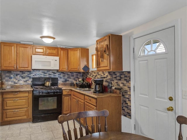 kitchen with brown cabinetry, black range with gas stovetop, white microwave, and tasteful backsplash