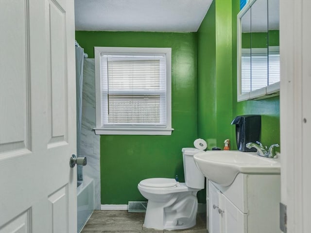 full bath with vanity, wood finished floors, a healthy amount of sunlight, and toilet
