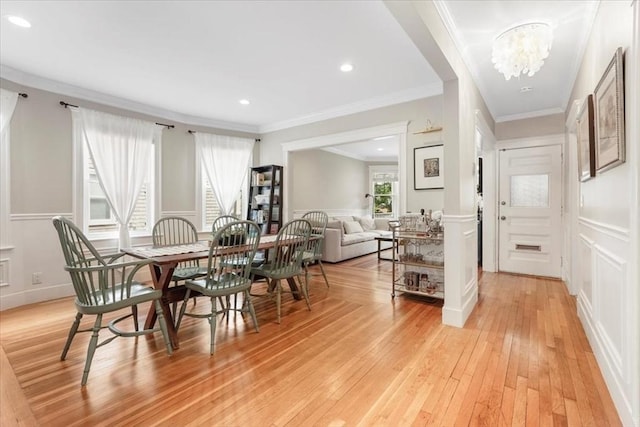 dining space featuring crown molding, light hardwood / wood-style flooring, and a notable chandelier