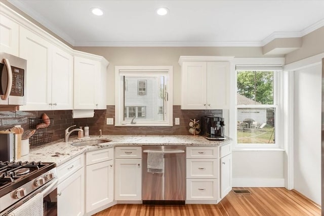 kitchen featuring light hardwood / wood-style flooring, white cabinetry, stainless steel appliances, and ornamental molding