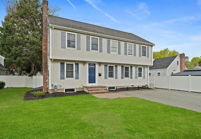 colonial inspired home with a chimney, a fenced backyard, and a front yard