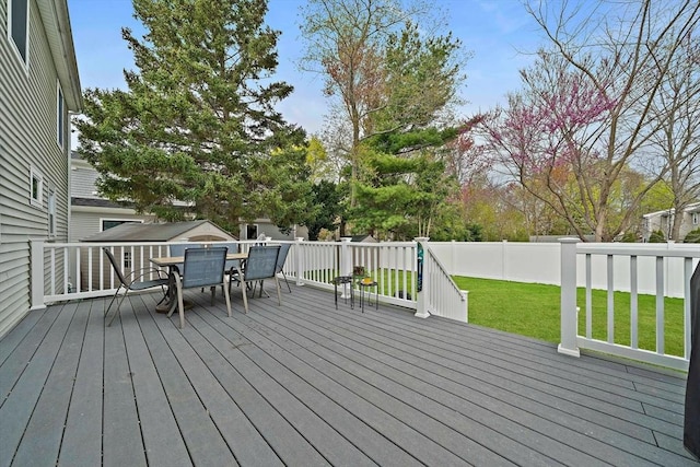 wooden terrace featuring a yard, outdoor dining space, and a fenced backyard