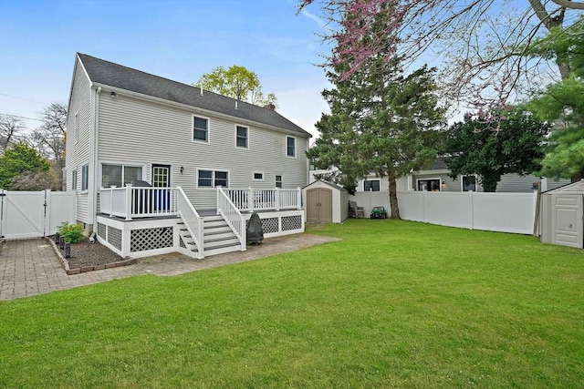 rear view of house with a fenced backyard, a gate, a shed, and a deck