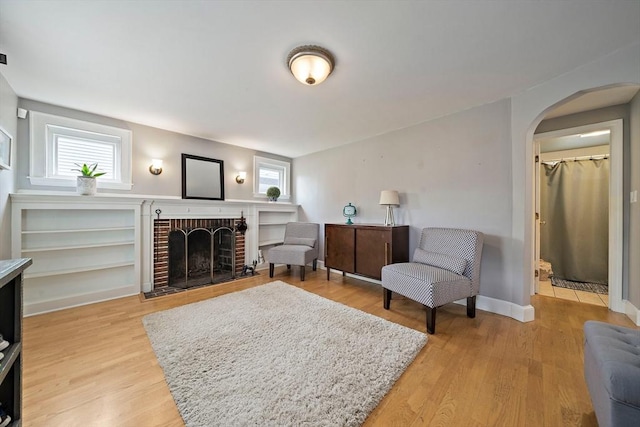 interior space with arched walkways, plenty of natural light, light wood finished floors, and a fireplace