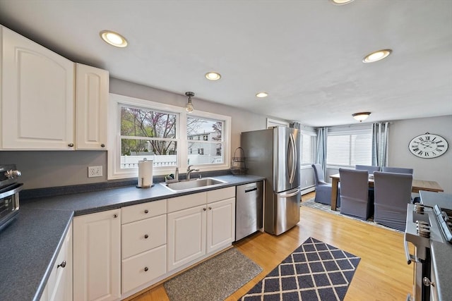 kitchen featuring stainless steel appliances, dark countertops, a healthy amount of sunlight, and a sink