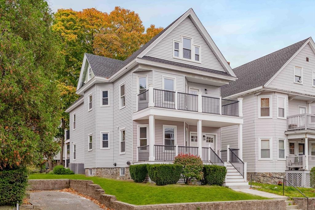 view of front of home with a porch, a balcony, central air condition unit, and a front yard