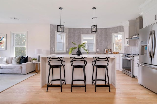 kitchen with a kitchen breakfast bar, appliances with stainless steel finishes, decorative light fixtures, a kitchen island, and white cabinetry