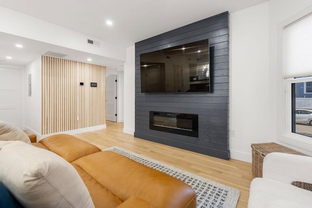 living room with a large fireplace and light hardwood / wood-style floors