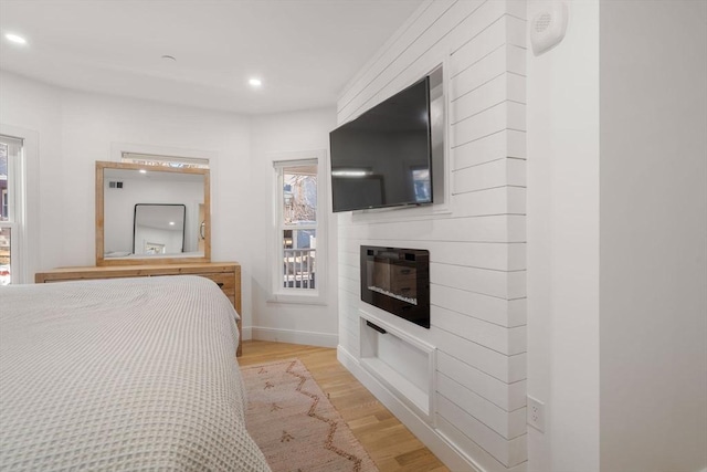 bedroom featuring light wood-type flooring and a fireplace