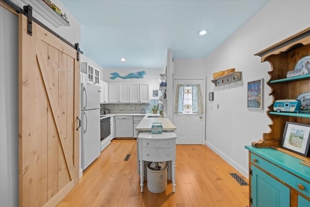 kitchen featuring white appliances, light countertops, light wood-style flooring, and a barn door