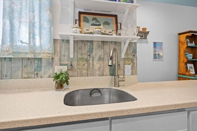 details featuring light stone counters, a sink, and white cabinets