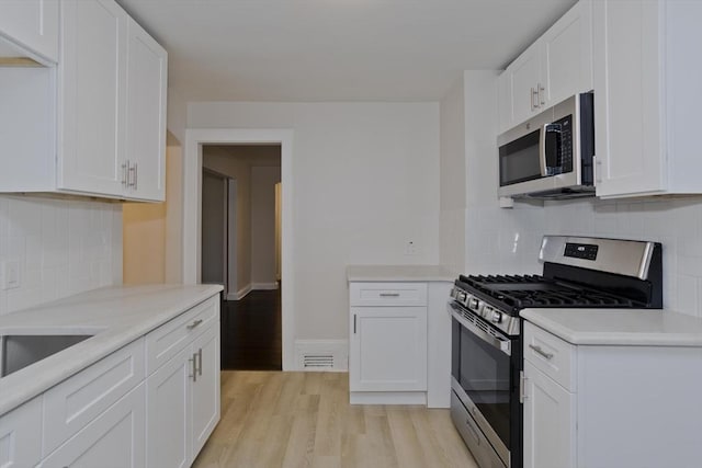 24 City View Ave, West Springfield, MA 01089 - kitchen featuring appliances with stainless steel finishes, light wood finished floors, white cabinets, light countertops, and backsplash
