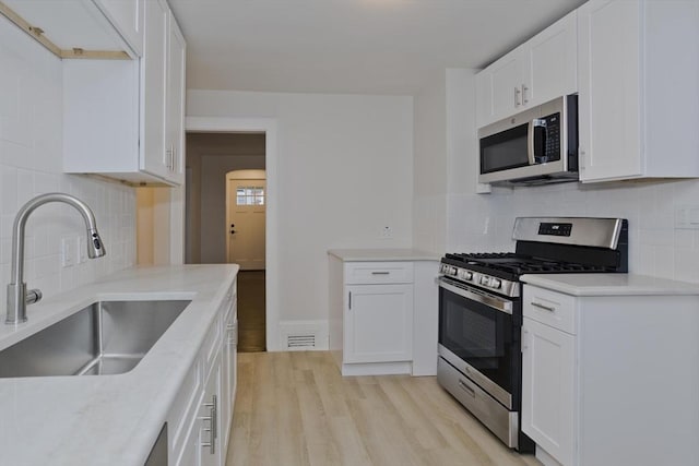 24 City View Ave, West Springfield, MA 01089 - kitchen with stainless steel appliances, decorative backsplash, light wood-style floors, white cabinetry, and light countertops