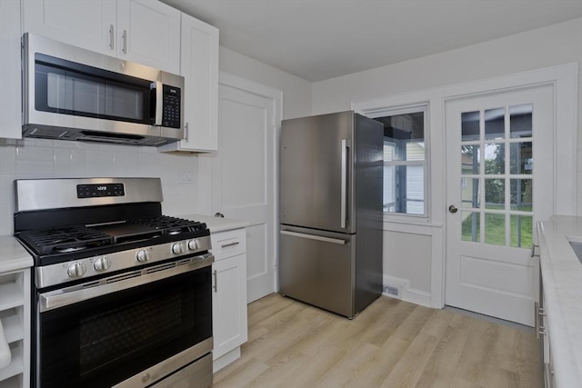 24 City View Ave, West Springfield, MA 01089 - kitchen with stainless steel appliances, light countertops, white cabinetry, light wood finished floors, and backsplash