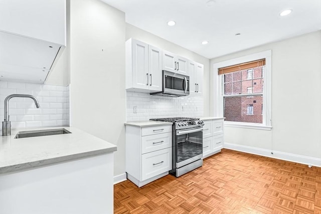 kitchen featuring a sink, stainless steel appliances, white cabinets, decorative backsplash, and baseboards