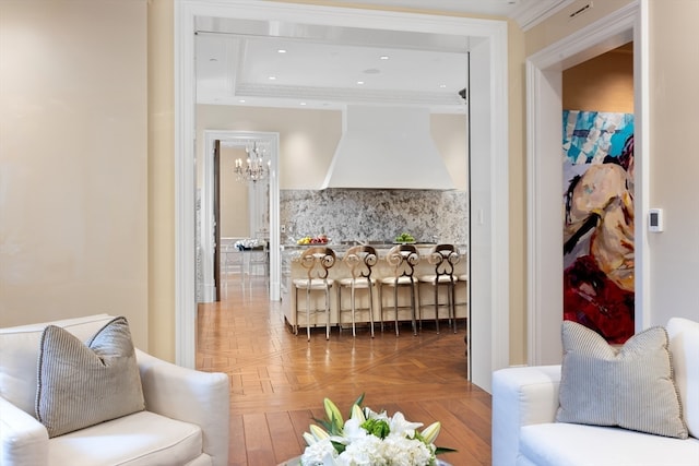 living room featuring a notable chandelier, a raised ceiling, parquet floors, and ornamental molding