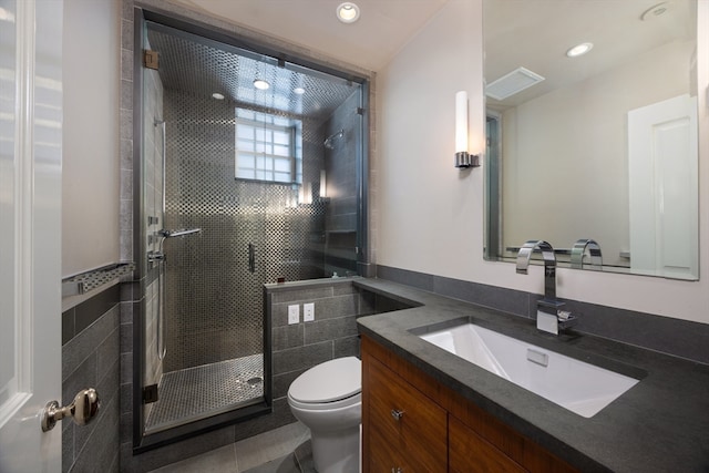 bathroom featuring tile patterned flooring, a shower with door, vanity, and toilet