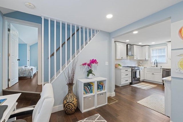 kitchen with white cabinetry, stainless steel appliances, dark wood-type flooring, and wall chimney range hood