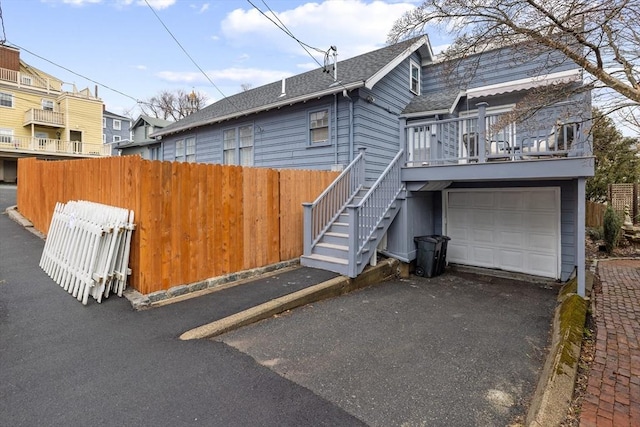 view of front of house with fence, aphalt driveway, stairs, roof with shingles, and a garage