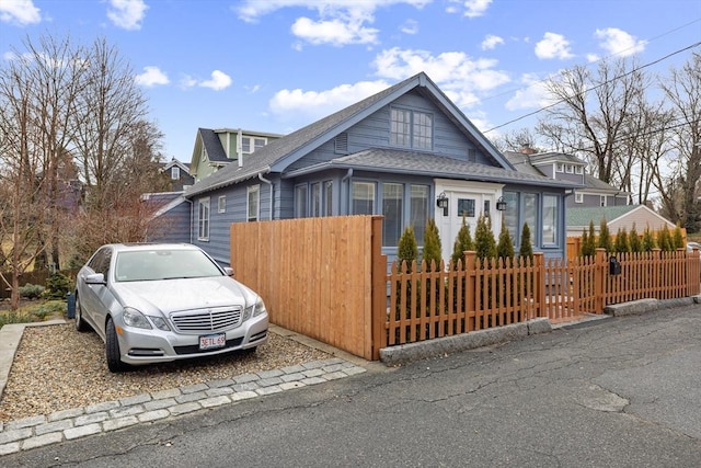 view of front of house featuring a fenced front yard and roof with shingles