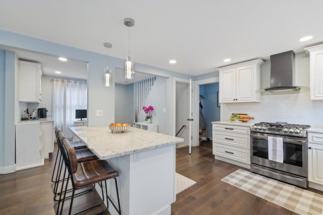 kitchen featuring gas stove, a kitchen island, dark wood-style flooring, a kitchen bar, and wall chimney exhaust hood