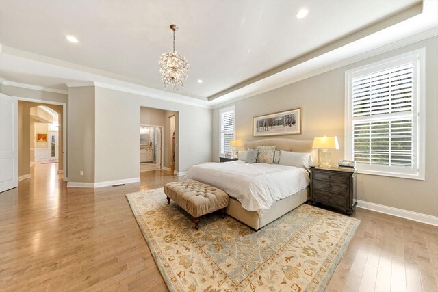 bedroom with crown molding, arched walkways, light wood-style flooring, and multiple windows