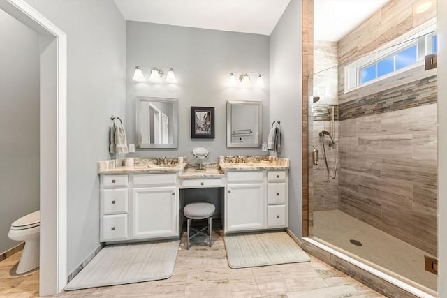 full bathroom with vanity, wood finished floors, toilet, baseboards, and a shower stall