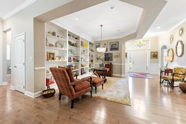 living area with wood-type flooring and ornamental molding