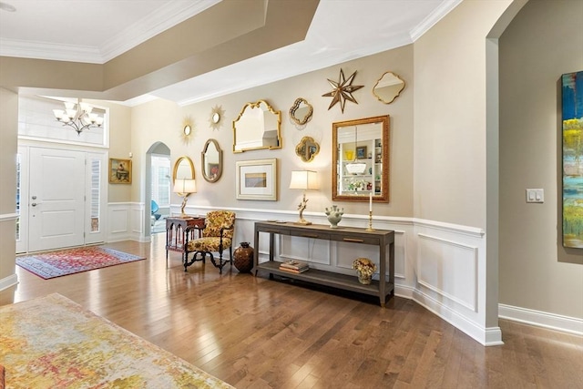 foyer entrance with arched walkways, hardwood / wood-style flooring, and a notable chandelier