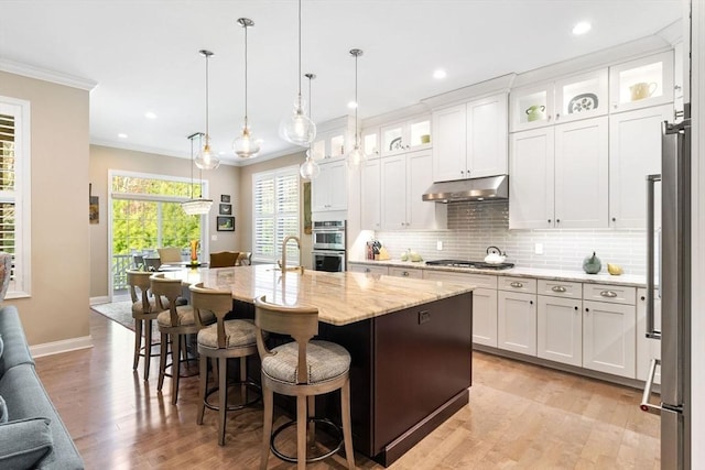 kitchen featuring crown molding, light wood-style flooring, under cabinet range hood, and white cabinets
