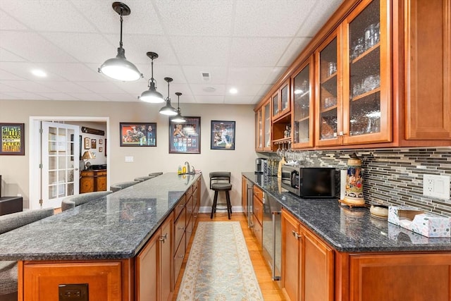 bar with a paneled ceiling, light wood-style flooring, baseboards, stainless steel microwave, and decorative backsplash